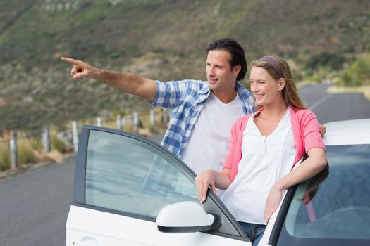 smiling couple looking away outside their car