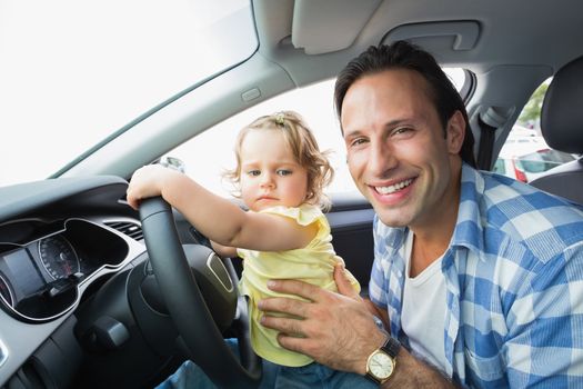 Father playing with baby in drivers seat in his car