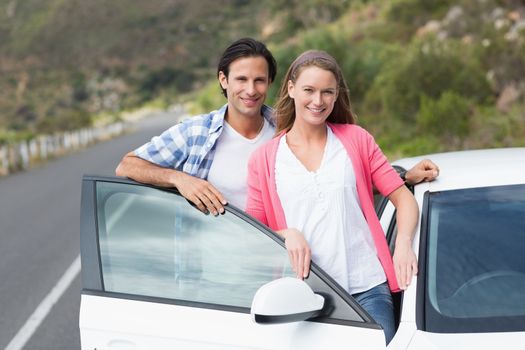 Couple smiling at the camera outside their car