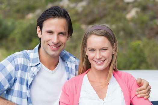 Couple smiling at the camera outside their car