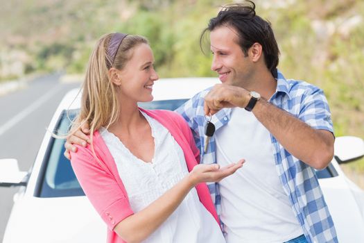 Couple holding key outside their car 