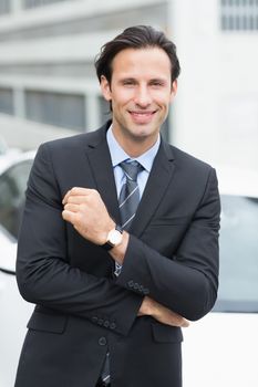 Businessman smiling at camera outside his car