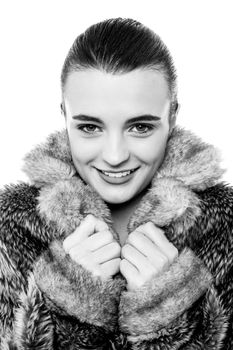 Smiling young female in warm fur jacket, black and white photo.