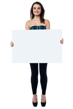 Full length shot of young girl displaying blank white ad board.