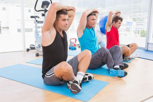 Group of men working on exercise mat in fitness studio 