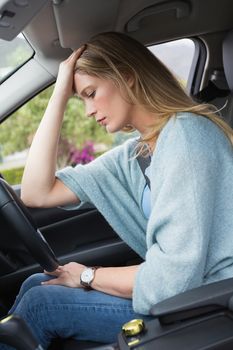 Worried woman sitting in drivers seat in her car