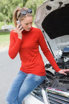 Young woman looking at engine of her car