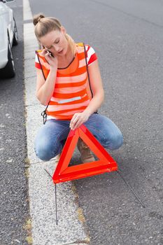 Young woman calling with her mobile phone beside her broken down car