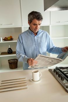 man reading a newspaper in the kitchen