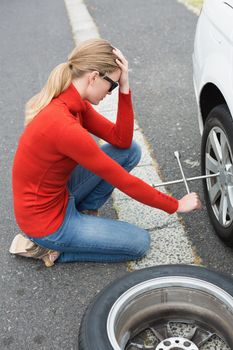 Annoyed woman trying to replace tire of her car 