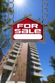 Grey metallic meter ruler in the shape of house with text for sale. For sale real estate sign with tall and blurred building in the background