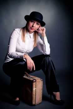 studio shot of gangster styled women sit on suitcase