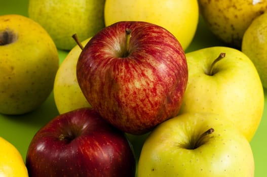 red and green apples on a green floor and a whole pear