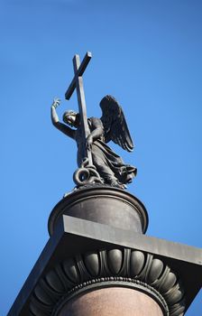 statue of winged angel with cross in blue sky 