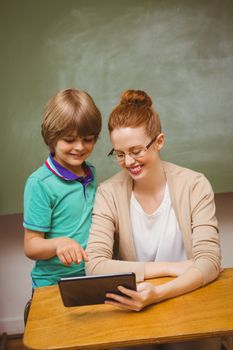 Portrait of female teacher and boy using digital tablet in the classroom