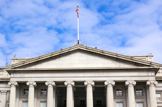 US Treasury Department Front Columns and Flag Pennsylvania Ave Washington DC.  The Treasury is located next to the White House because President Andrew Jackson told his advisors that he wanted the National Bank to be right there where he could see it.