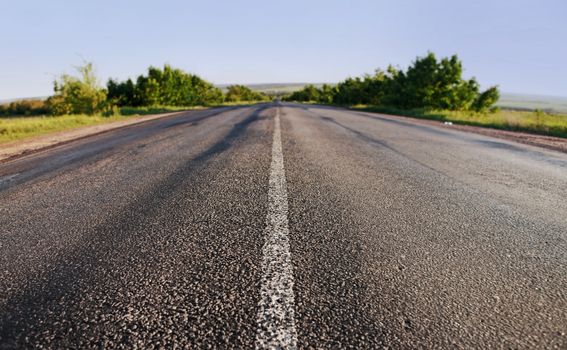 asphalt road through the green field on blue sky in summer day