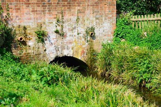 Red brick bridge over small stream