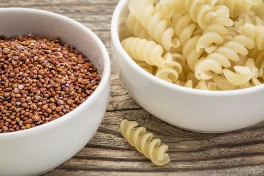 healthy, gluten free quinoa grain and pasta - small ceramic bowls against grained wood