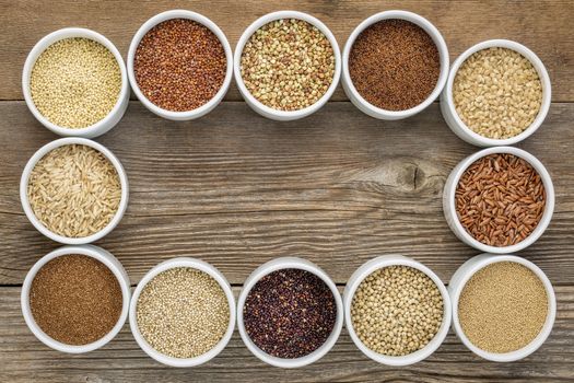 healthy, gluten free grains collection (quinoa, brown rice, millet, amaranth, teff, buckwheat, sorghum) , top view of small round bowls against rustic wood with a copy space