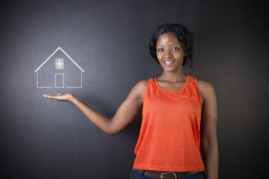 South African or African American woman teacher, student, saleswoman or businesswoman against black background holding house, home or real estate