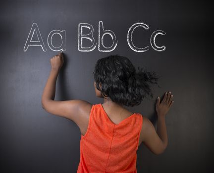 South African or African American woman teacher or student learn alphabet write writing on chalk blackboard background