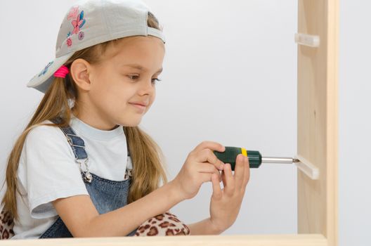 Six year old girl playing and collecting wooden cabinet