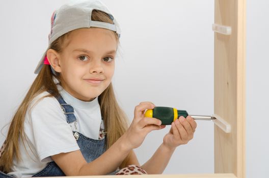 Six year old girl playing and collecting wooden cabinet