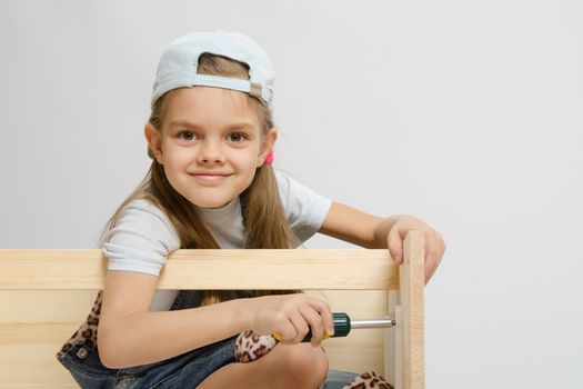 Six year old girl playing and collecting wooden cabinet