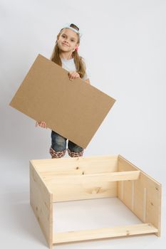 Six year old girl playing and collecting wooden cabinet