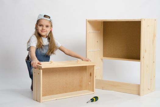 Six year old girl playing and collecting wooden cabinet