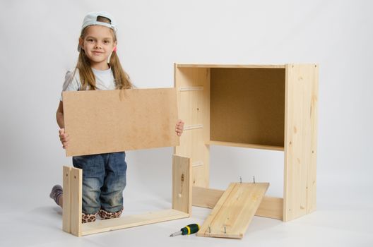 Six year old girl playing and collecting wooden cabinet