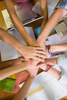 Close up of college students placing hands together over library table