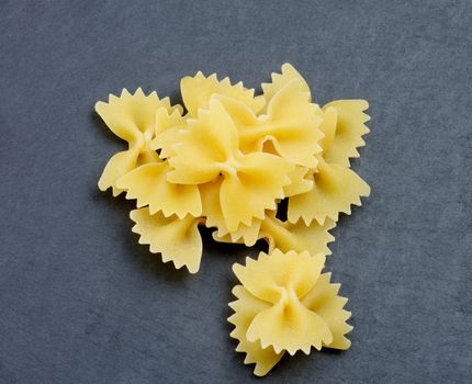 Arrangement of Raw Farfalle Pasta closeup on Black Stone background. Top View