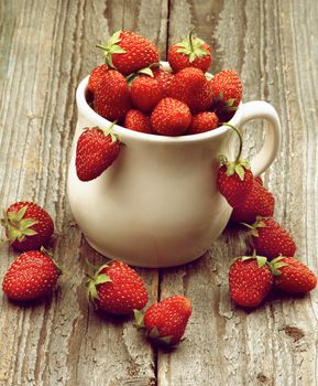 Heap of Fresh Ripe Forest Strawberries in White Bowl closeup on Rustic Wooden background. Retro Styled