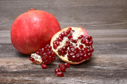 Red juicy pomegranate, on dark rustic wooden table