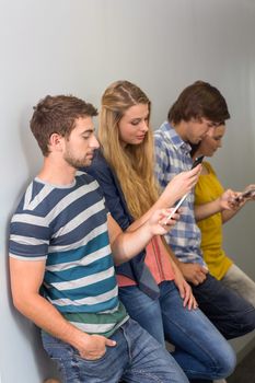 Side view of college students using cellphones