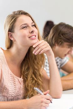 Side view of female student writing notes in classroom