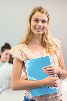 Portrait of happy female student holding folder in college