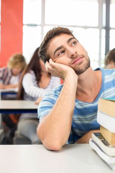 Thoughtful male student with books in the classroom