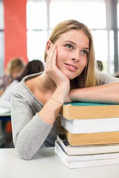 Thoughtful female student with books in the classroom