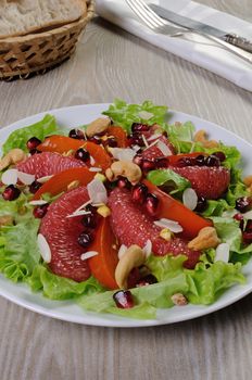 Salad of grapefruit and persimmon in lettuce leaves with cashews, almonds, pomegranate