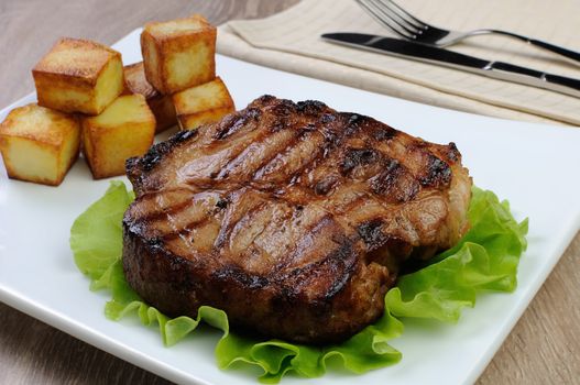 piece of juicy pork steak grilled with roasted potatoes
