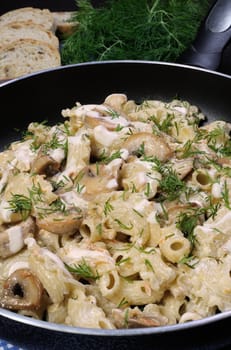 Pasta sauce with mushrooms in a pan on the table with bread and dill