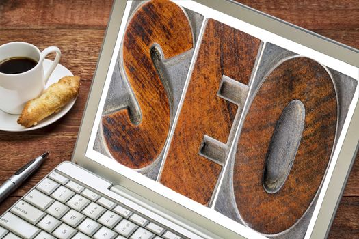 search engine optimization (SEO) -  text in vintage letterpress wood type on a laptio screen with a cup of coffee