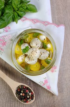 Baby mozzarella in olive oil with herbs in a glass jar