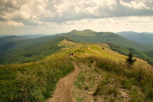 Poland,summer.Tourist path in Bieszczady mountin.Far one can see the group of tourists going along the trail into the bottom.Horizontal view.