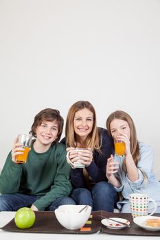Mom with your two sons drinking juice in the breakfast