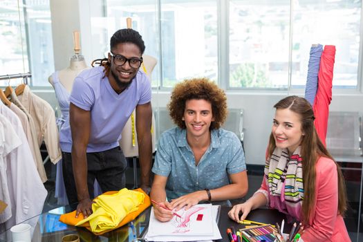 Team of young fashion designers sketching at table