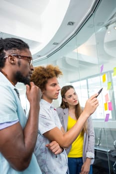 Creative business team pointing at adhesive notes in office